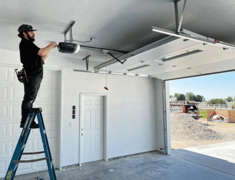 A technician is installing a new residential garage door opener system, a mechanically intense component that can weigh hundreds of pounds depending on insulation.