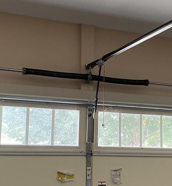 Broken Extension Spring: The visible garage door spring is likely broken, as indicated by the gap in the coiled metal.