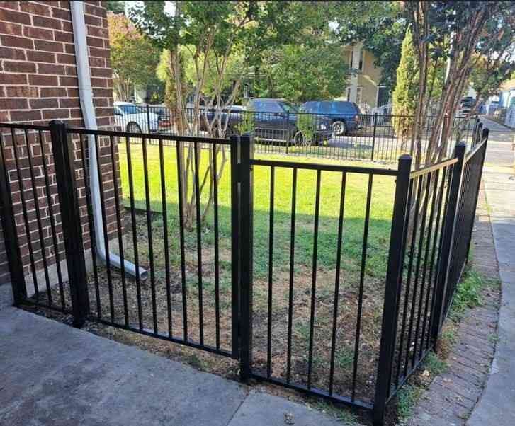 This black aluminum fence features a two-rail, flat-top design with a functional gate, offering a low-maintenance security solution for residential properties